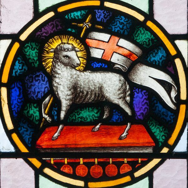 Stained-glass Agnus Dei: a haloed lamb carrying a cross-banner.